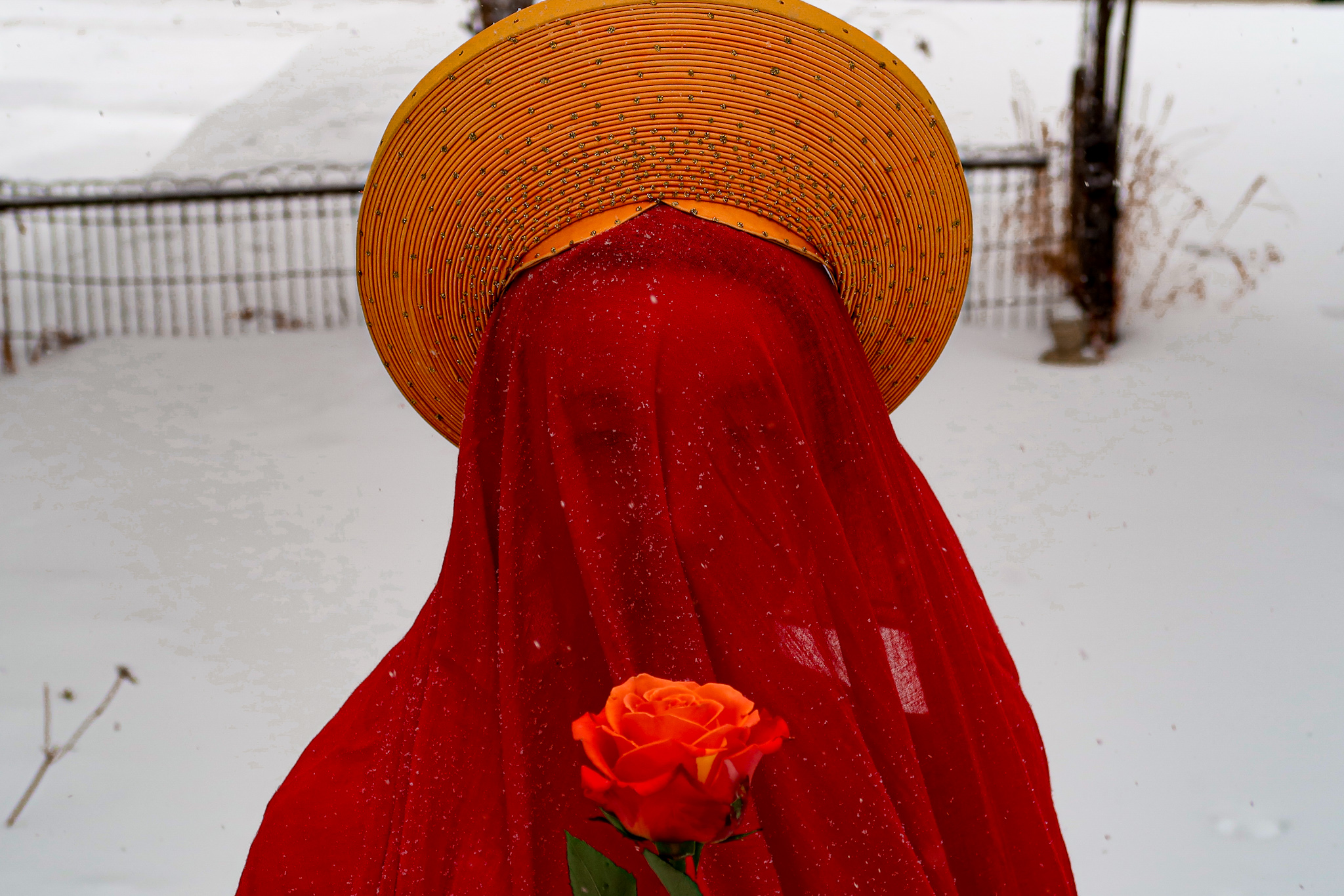 Sophia Terazawa performing in snow, veiled in red with a conical hat and rose — Minneapolis, 2021. Photo by Callisto Moses.